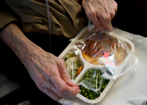Photo of a seniors hands opening a meals on wheels meal