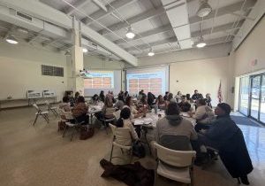 Photo of about 50 people from different orgs sitting around tables in the Glouster HAPCAP office to discuss Sunset Shelter partnership.