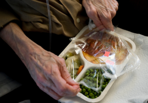 Photo of a seniors hands opening a meals on wheels meal